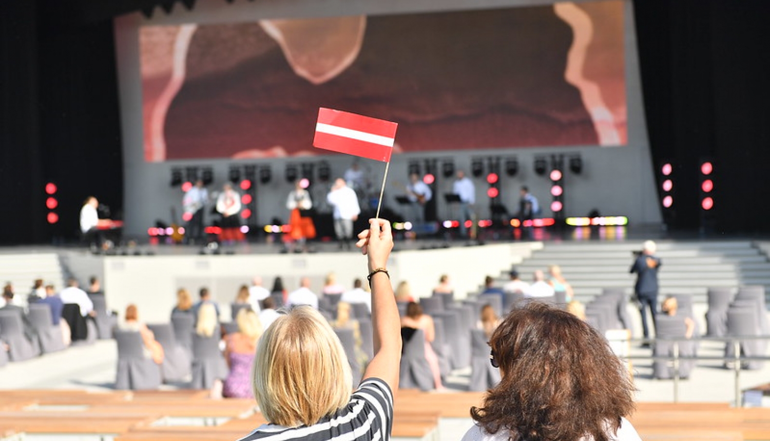 sieviete tur rokā Latvijas karogu